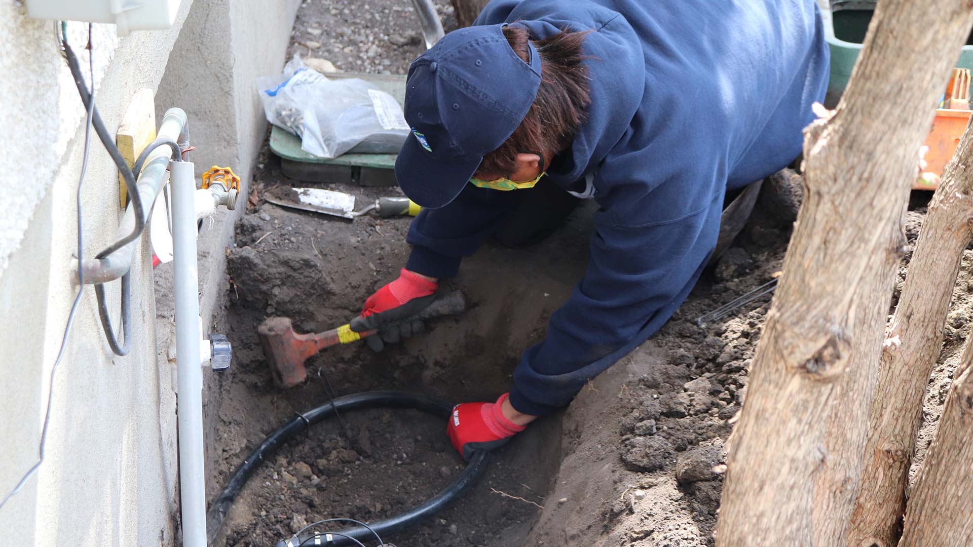 Irrigation expert repairing system by house near Southwood, Calgary, AB.