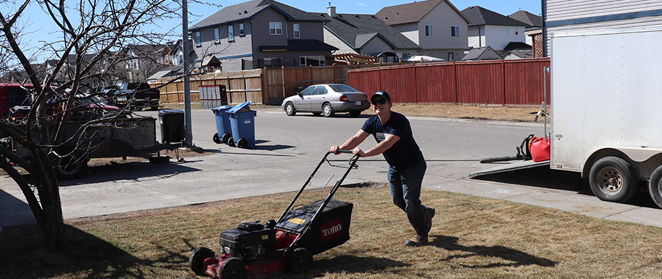 content prestige employee pushing lawn mower 2