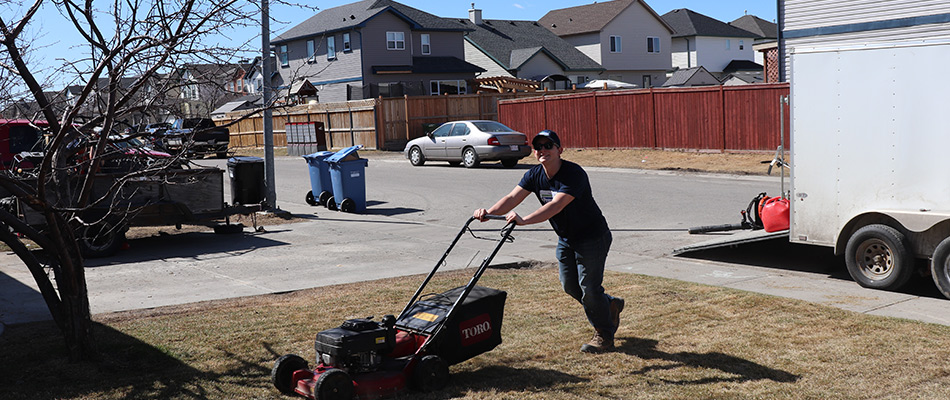 content prestige employee pushing lawn mower